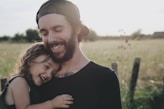 man carrying daughter in black sleeveless top