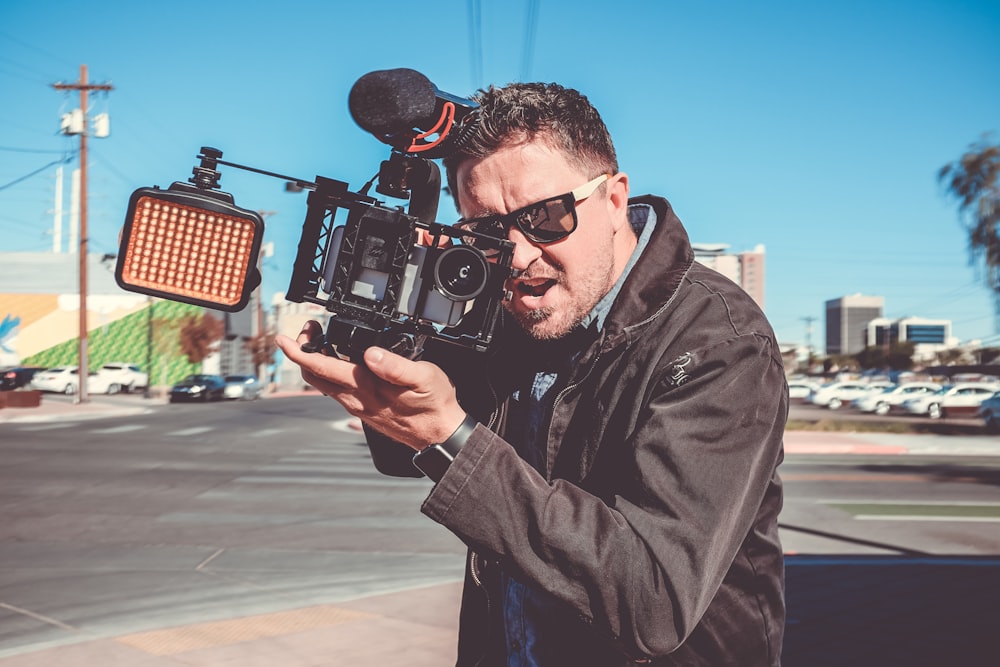 Fotografía de enfoque superficial de hombre sosteniendo cámara de video