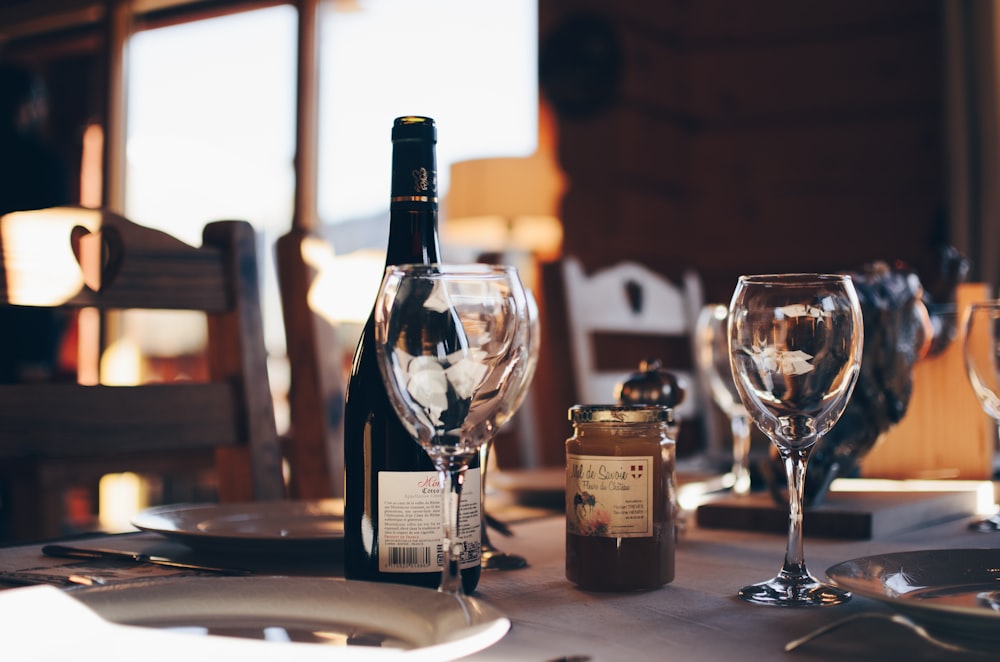 closeup photo of two empty wine glasses beside wine bottle