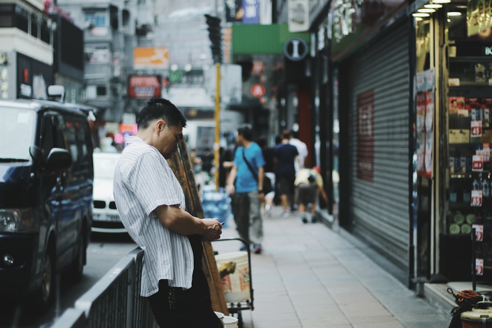 shallow photography of man leaning towards grey steel fence