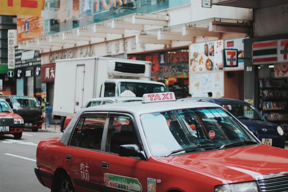 rot-weiße Taxi-Limousine fährt auf der Straße in der Nähe der Beschilderung des 7 Eleven-Geschäfts