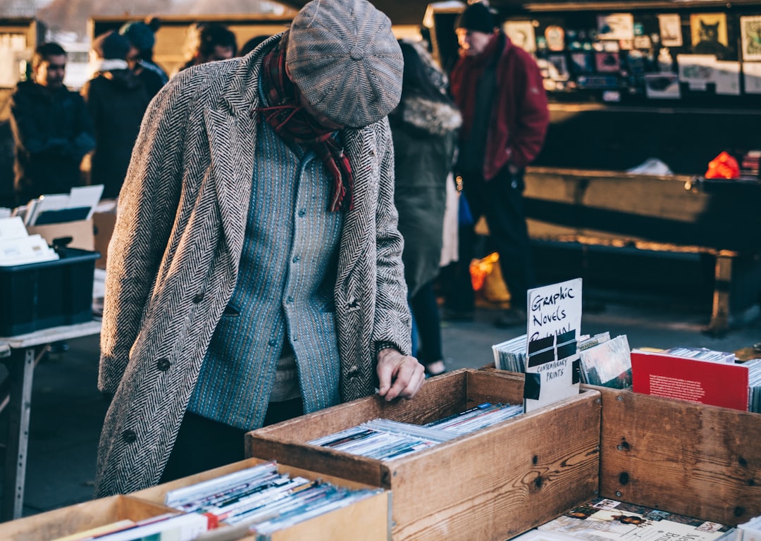 person looking in box filled with books, man in tweed