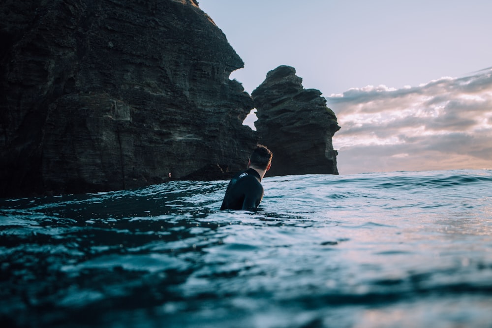 uomo che indossa un top nero che galleggia sullo specchio d'acqua durante il giorno