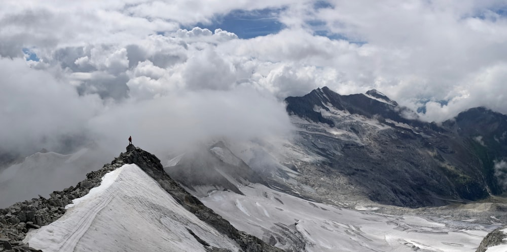 pessoa em pé no topo da montanha coberta de neve