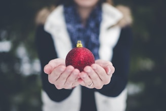 shallow focus photography of person holding bauble