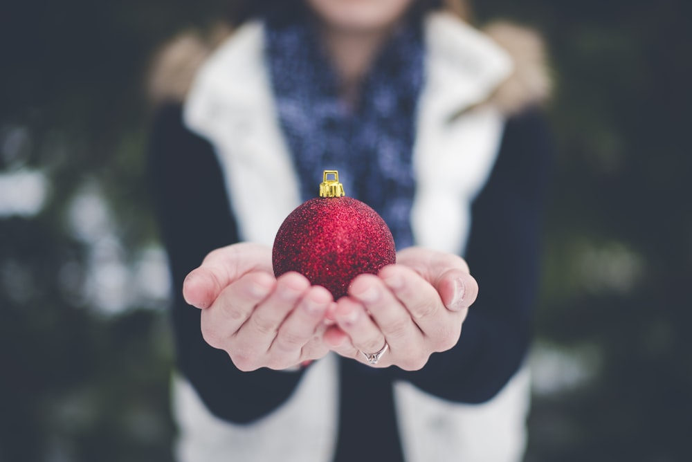shallow focus photography of person holding bauble