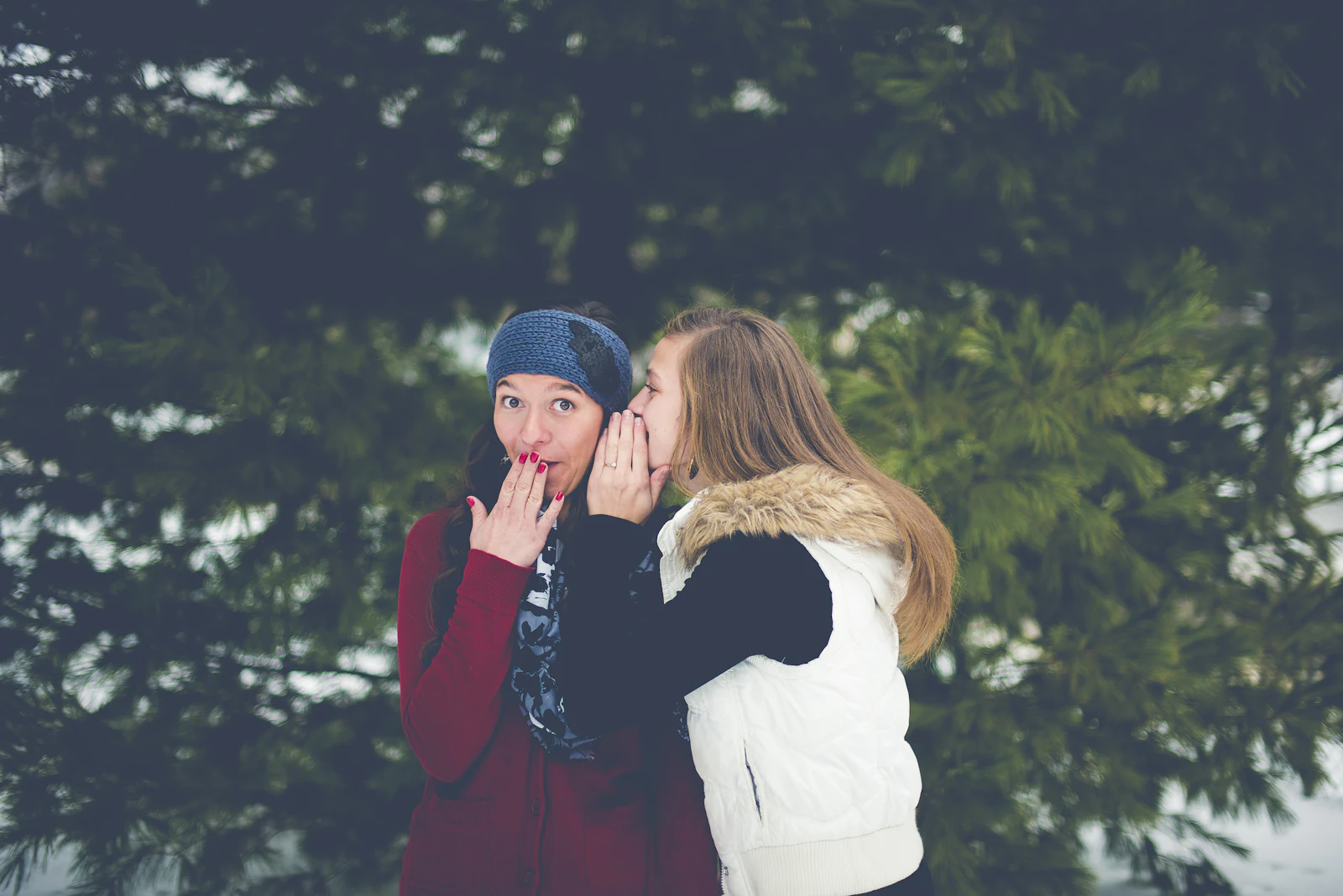 A woman whispering into a friend's ear