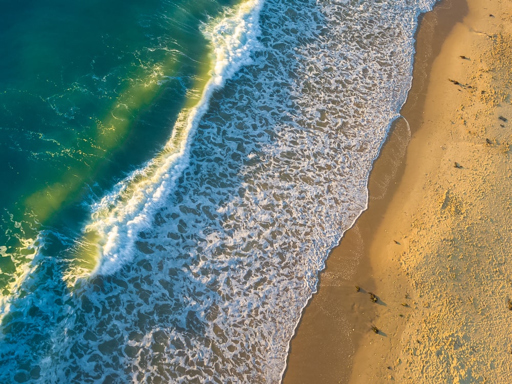 Foto aérea del mar verde y blanco con espuma en la costa durante el día