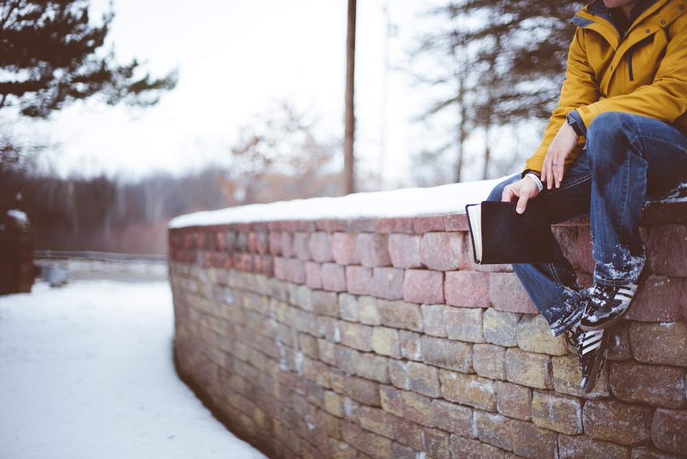 person sitting on brick wall