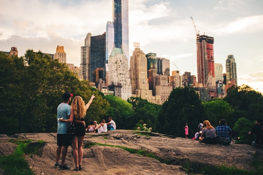 man and woman standing on hill looking at s skyscraper in Empire State Building United States