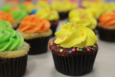 Colorful cupcakes lined up on a rustic tray, each topped with creamy frosting and sprinkles.