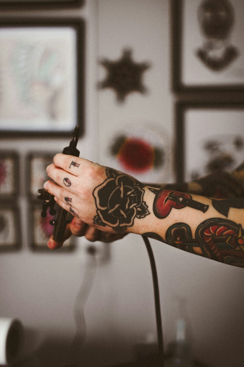 Fotografia de foco raso de pessoa segurando máquina de tatuagem preta