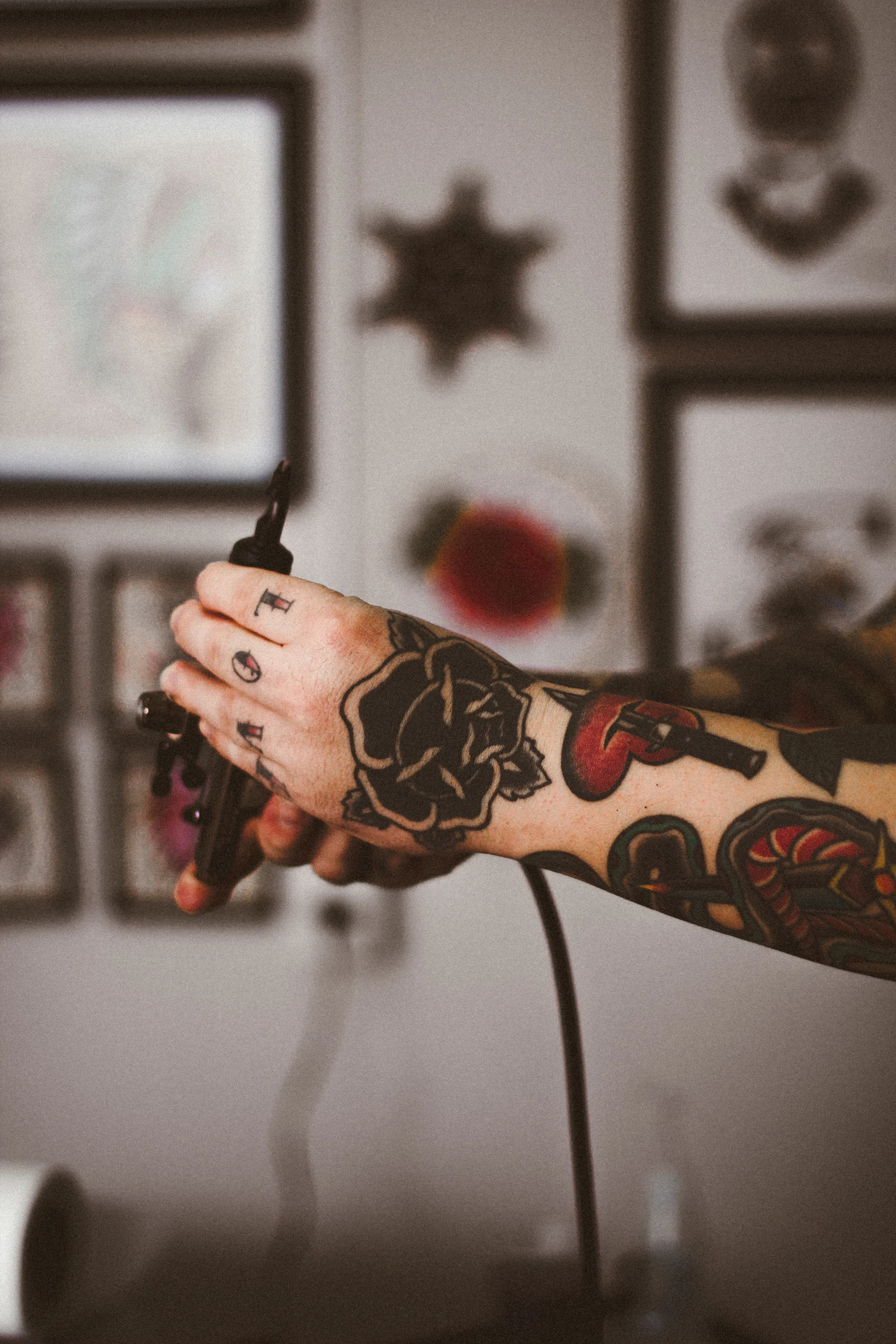 Mão tatuada segurando uma máquina de tatuagem