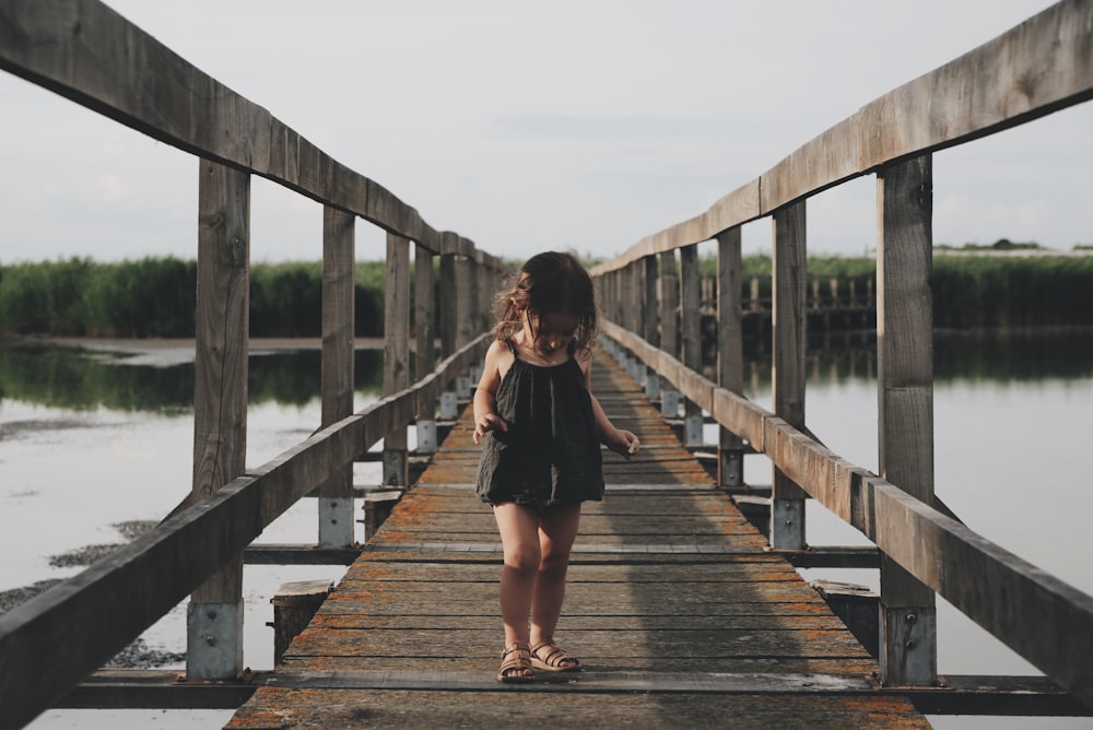 girl wearing black camisole walking on dock