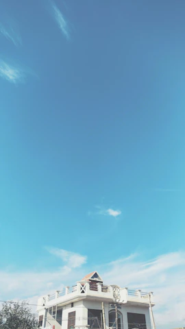 The exterior of a bright blue house with crisp white accents under a clear sky.