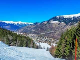 Snow-capped Alps with a family skiing down gentle slopes.