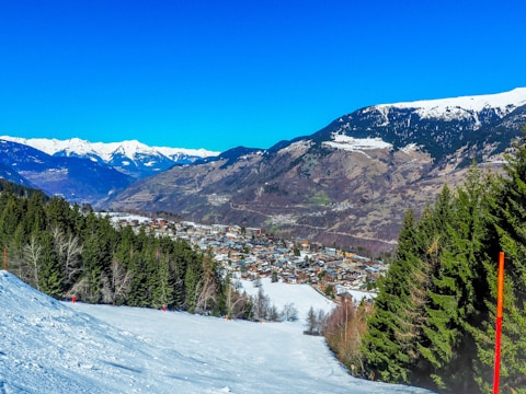Snow-capped Alps with a family skiing down gentle slopes.