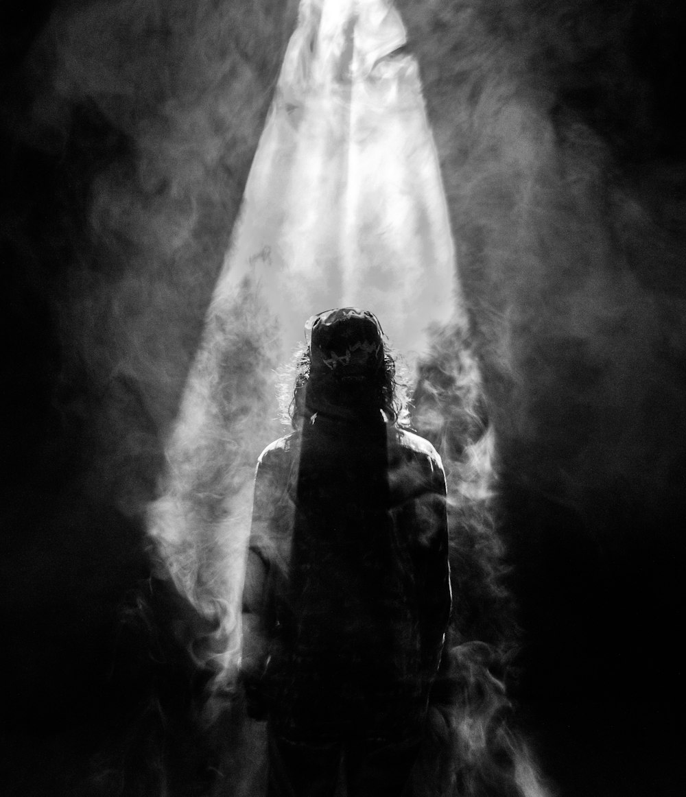 Photographie d’une personne faisant face à face dans un projecteur enfumé