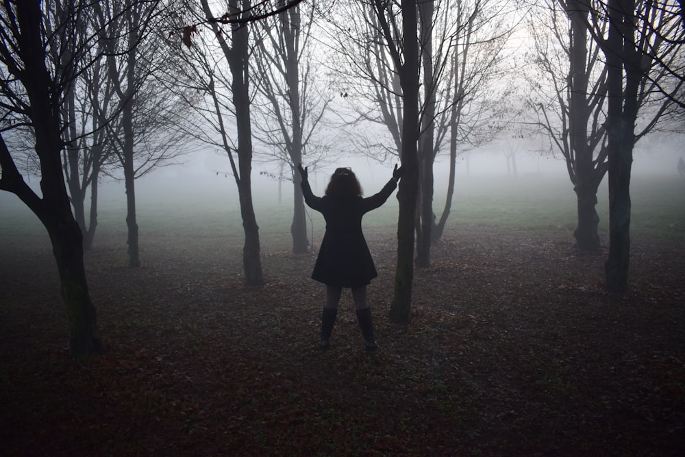 person standing beside black trees photography