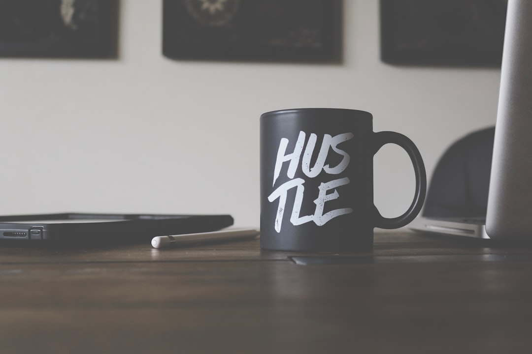 black and white Hustle-printed ceramic mug on table