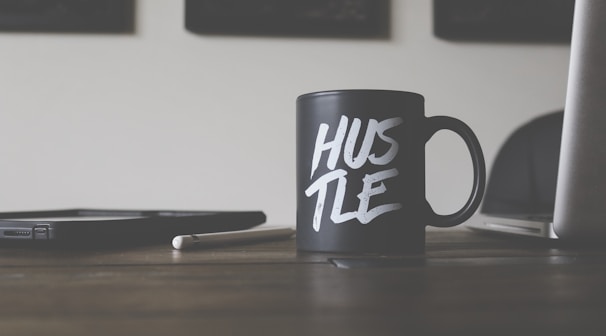 black and white Hustle-printed ceramic mug on table