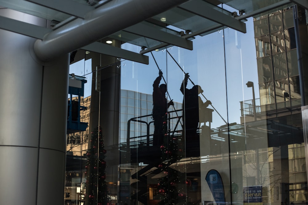 homem utilitário em pé na plataforma de tesoura limpando janela de vidro