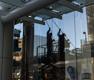 utility man standing in scissor platform cleaning glass window