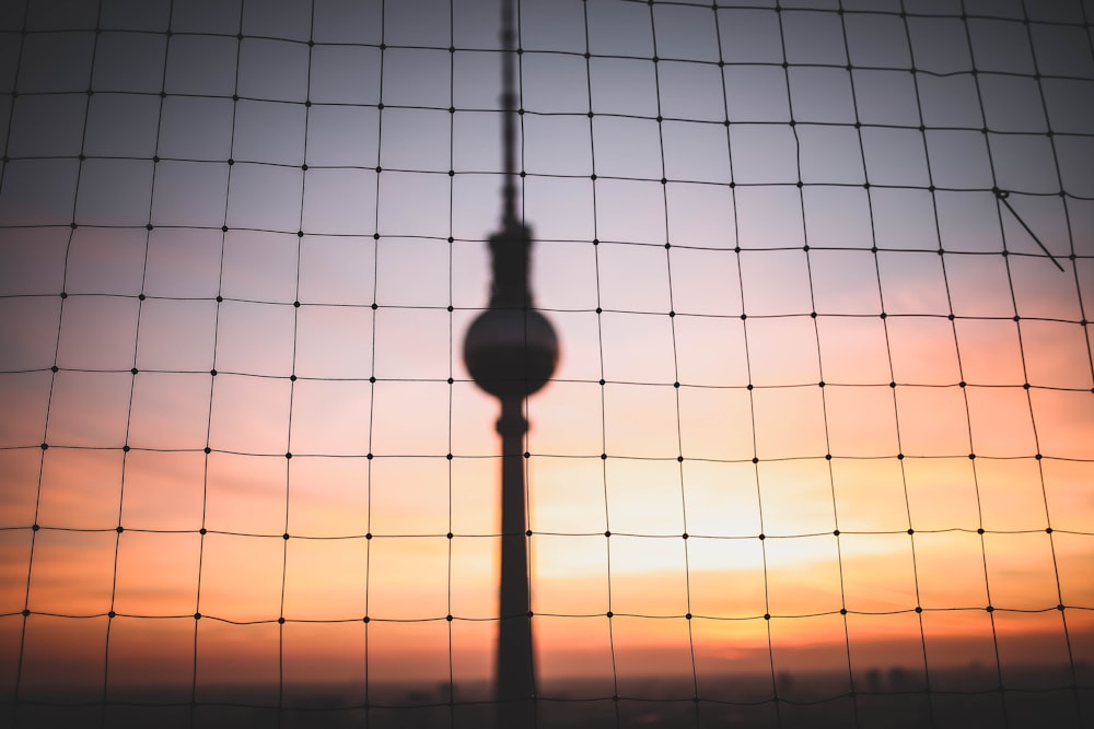 Silhouettenfoto von hängendem Dekor hinter Maschendrahtzaun zur goldenen Stunde