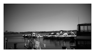 Black and white photo of a sleek luxury yacht moored in calm waters at dusk.