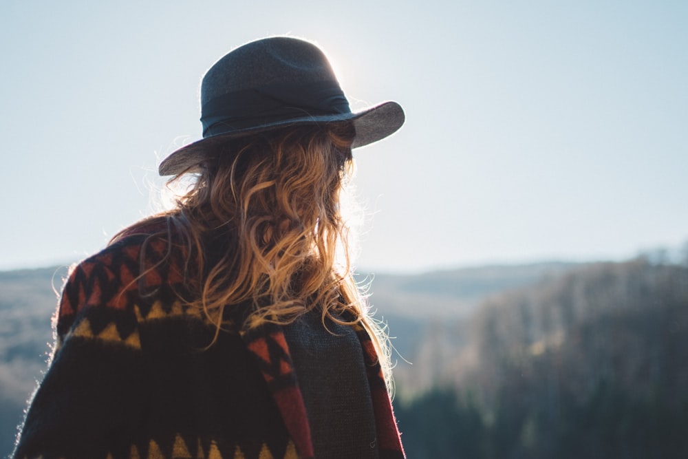 Foto de persona con cabello rubio con sombrero mirando al horizonte