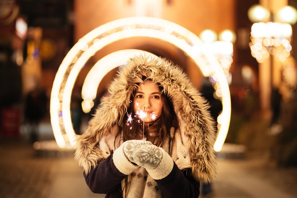 donna che indossa cappotto e tiene fuochi d'artificio