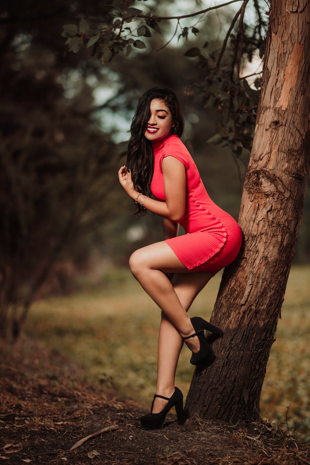 woman in red long sleeve dress sitting on tree