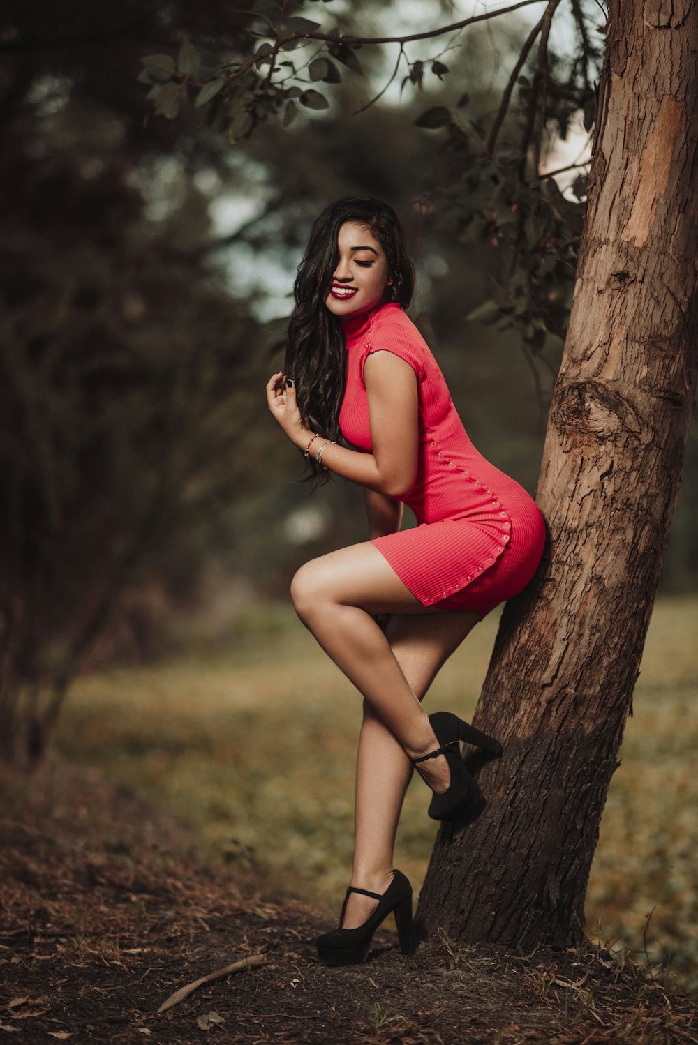 woman in red long sleeve dress sitting on tree