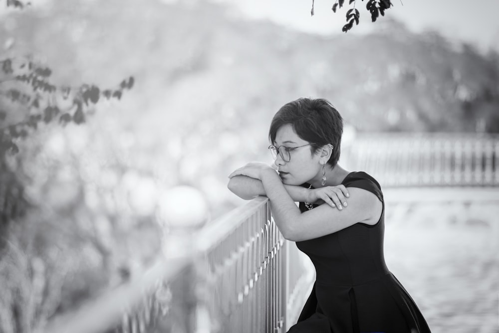 woman in black spaghetti strap dress standing beside railings