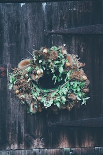 A rustic wreath made from dried flowers and foliage on a wooden door