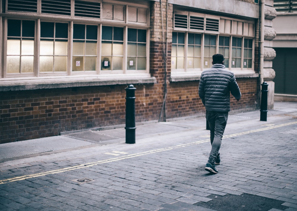 昼間、茶色のコンクリートの建物の横を歩く男性