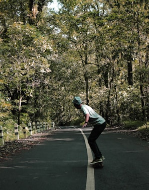 Action shot of a skater cruising on a mini cruiser down a tree-lined path.