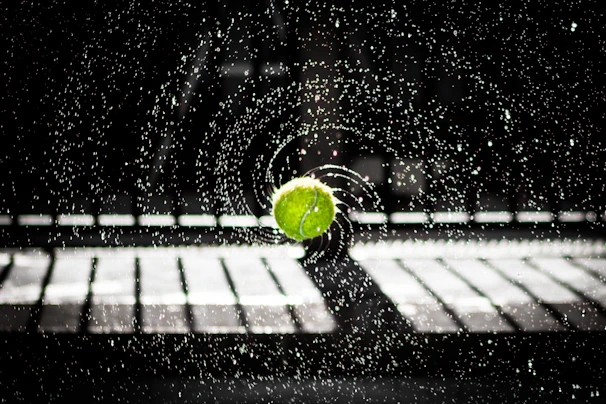 Close-up of a tennis ball mid-air just before impact with a racquet during an intense training drill