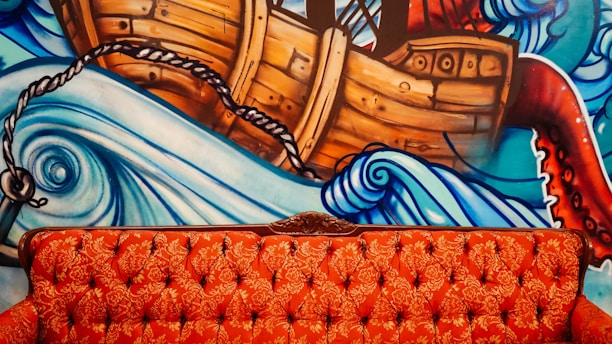 tufted orange sofa with brown boat mural paint in the back