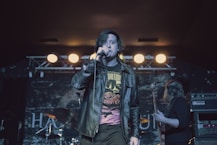 man in black leather jacket singing with microphone