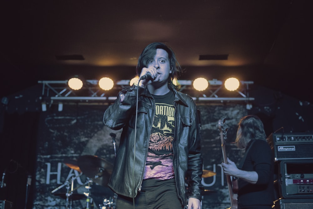 man in black leather jacket singing with microphone