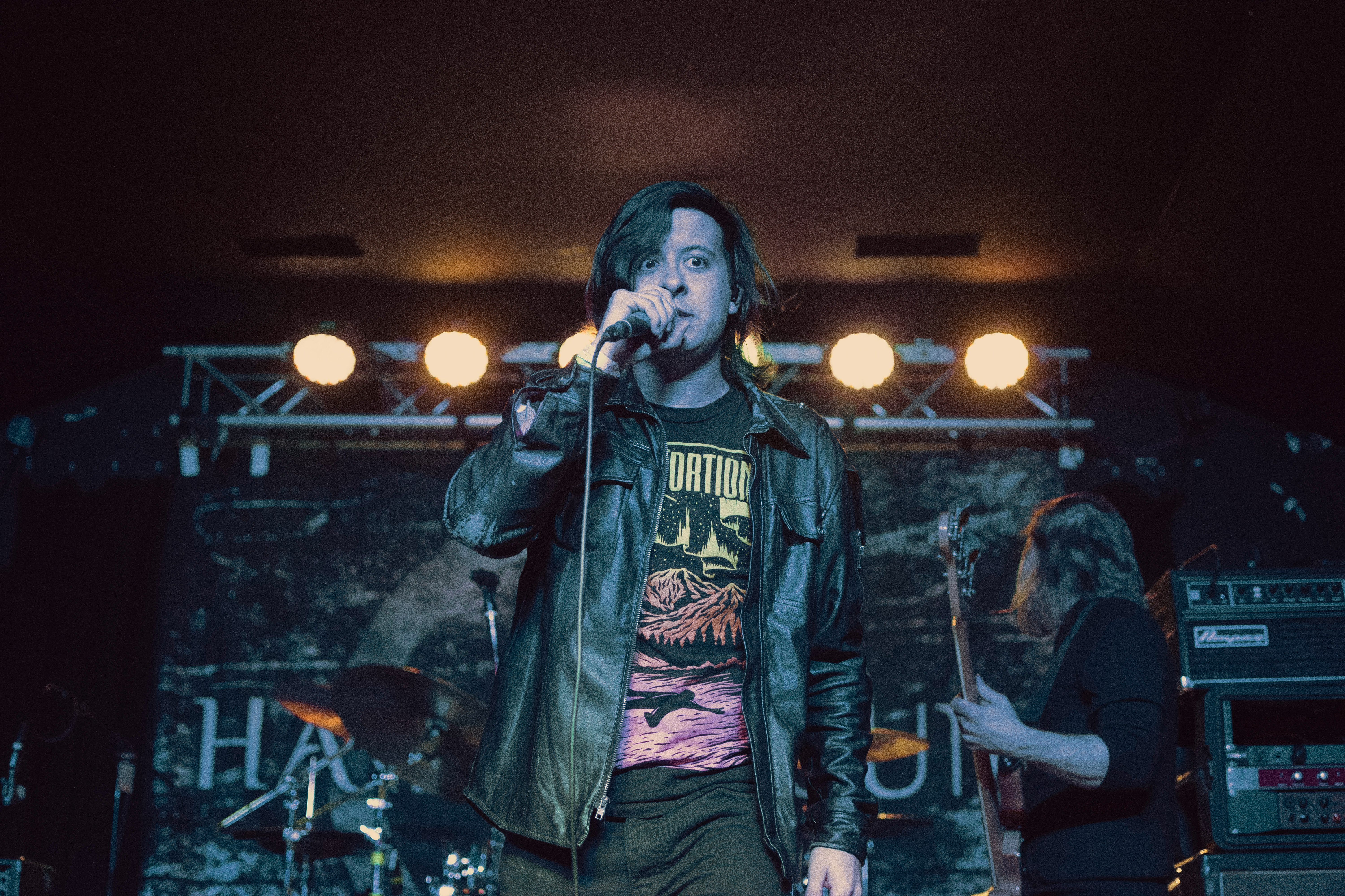 man in black leather jacket singing with microphone