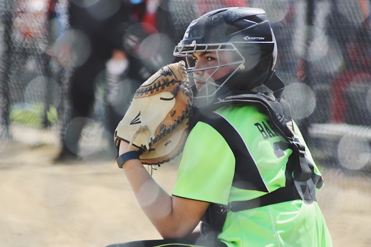 Baseball catcher on the field in action: young girl, maybe 11?in protective gear. Green tshirt, new glove.