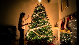 child standing in front of Christmas tree with string lights