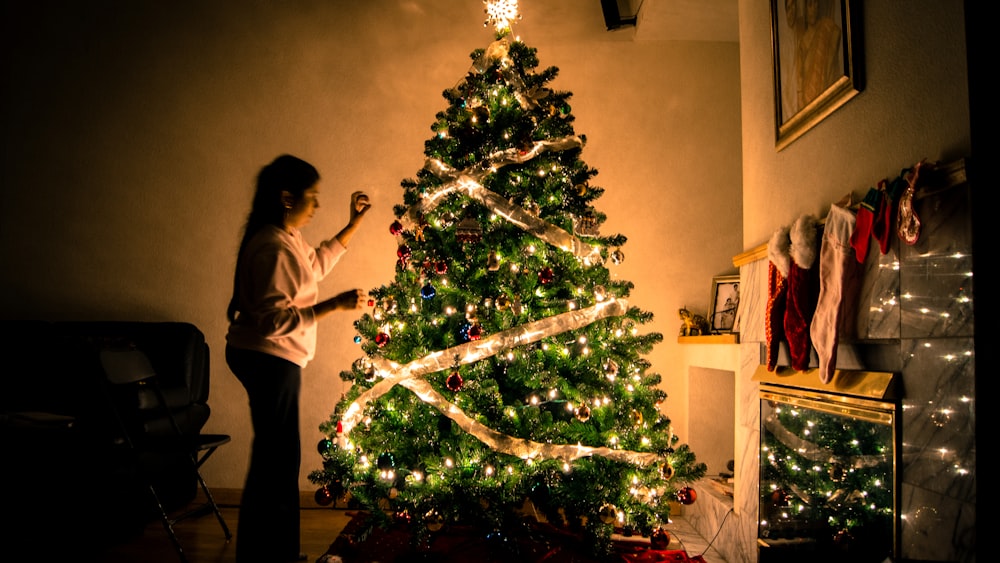 child standing in front of Christmas tree with string lights