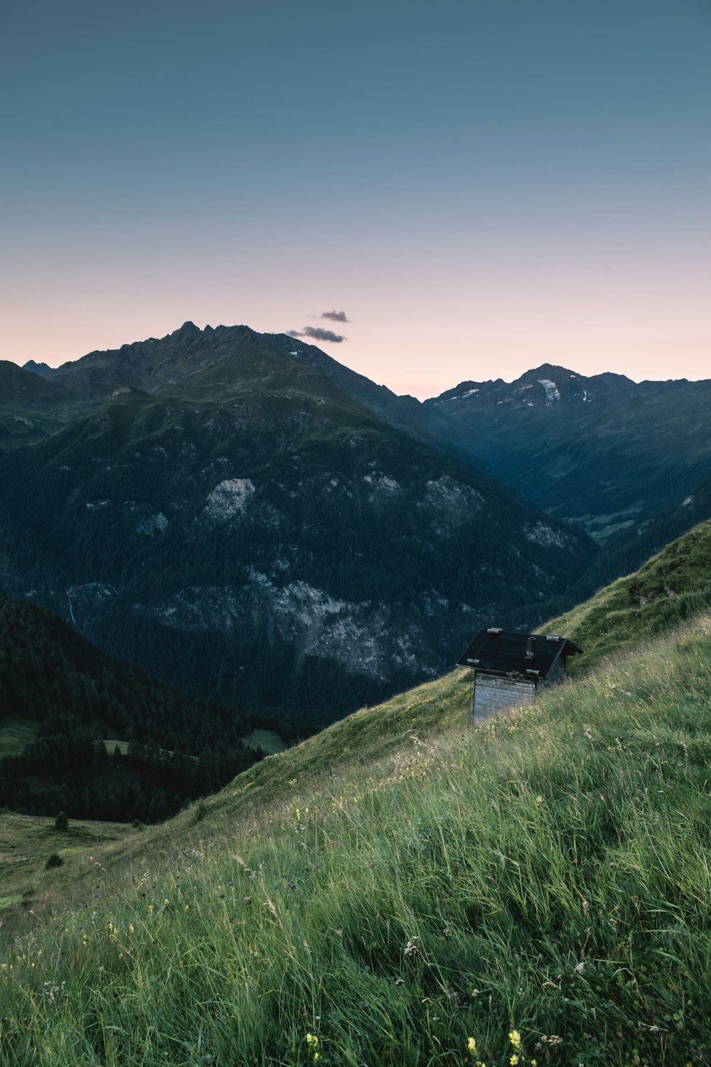 casa con tetto nero sul campo di erba verde durante il giorno