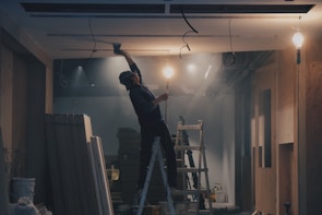 Close-up of a skilled worker fitting a suspended ceiling frame in a modern office space.