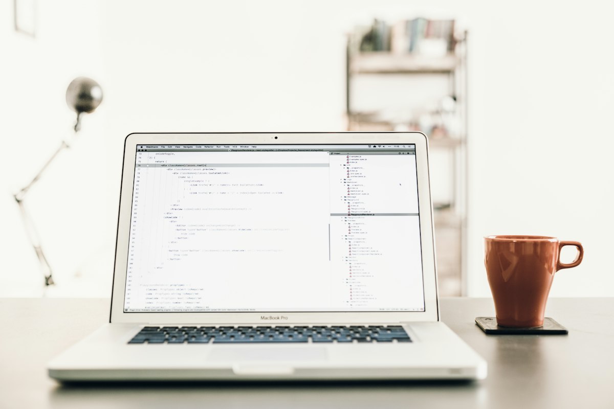 Laptop with code beside a brown mug