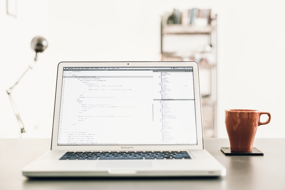 MacBOok Pro beside brown mug