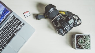 black nikon dslr camera beside silver macbook